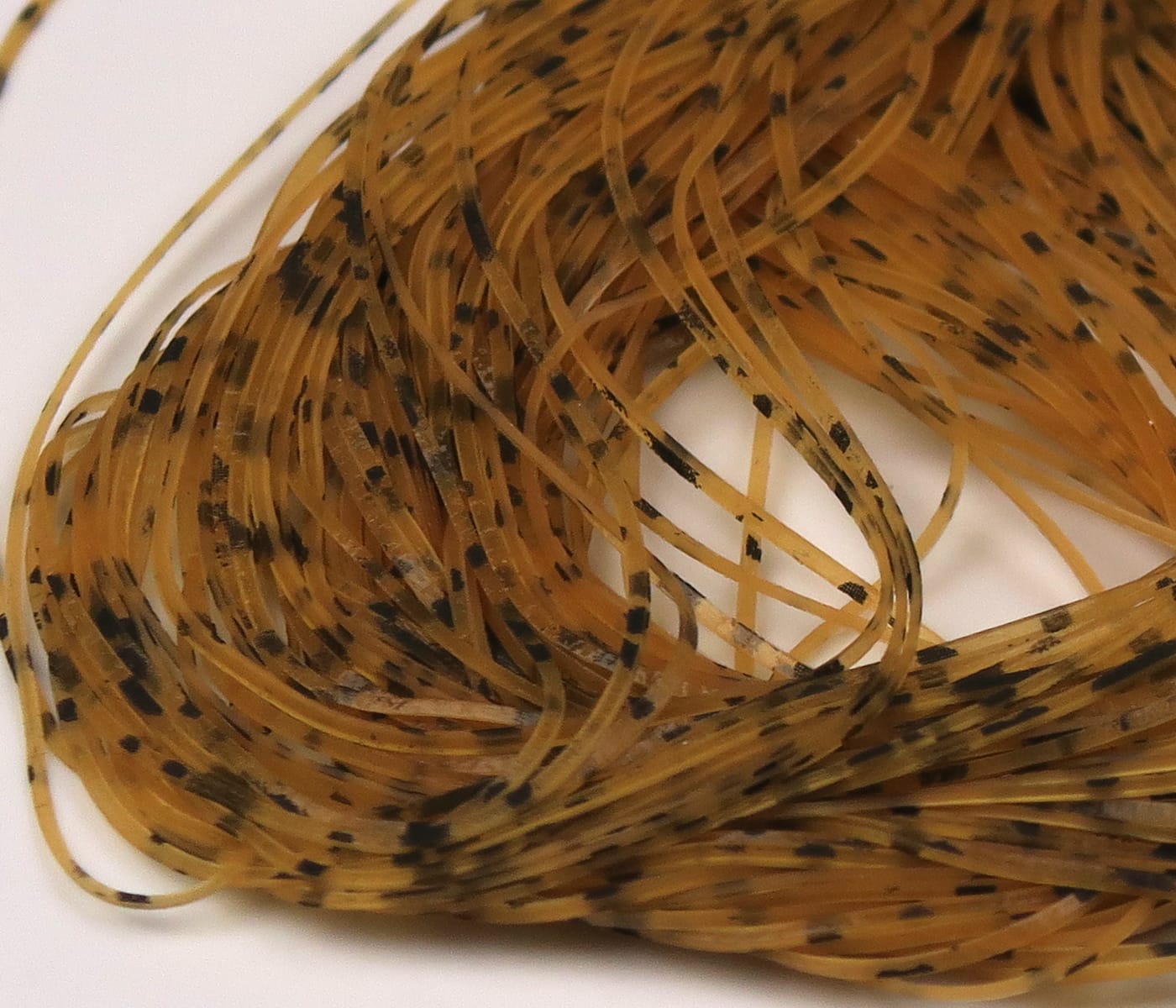 Amber translucent rubber nymph legs with black speckles, thin silicone strands for fly tying