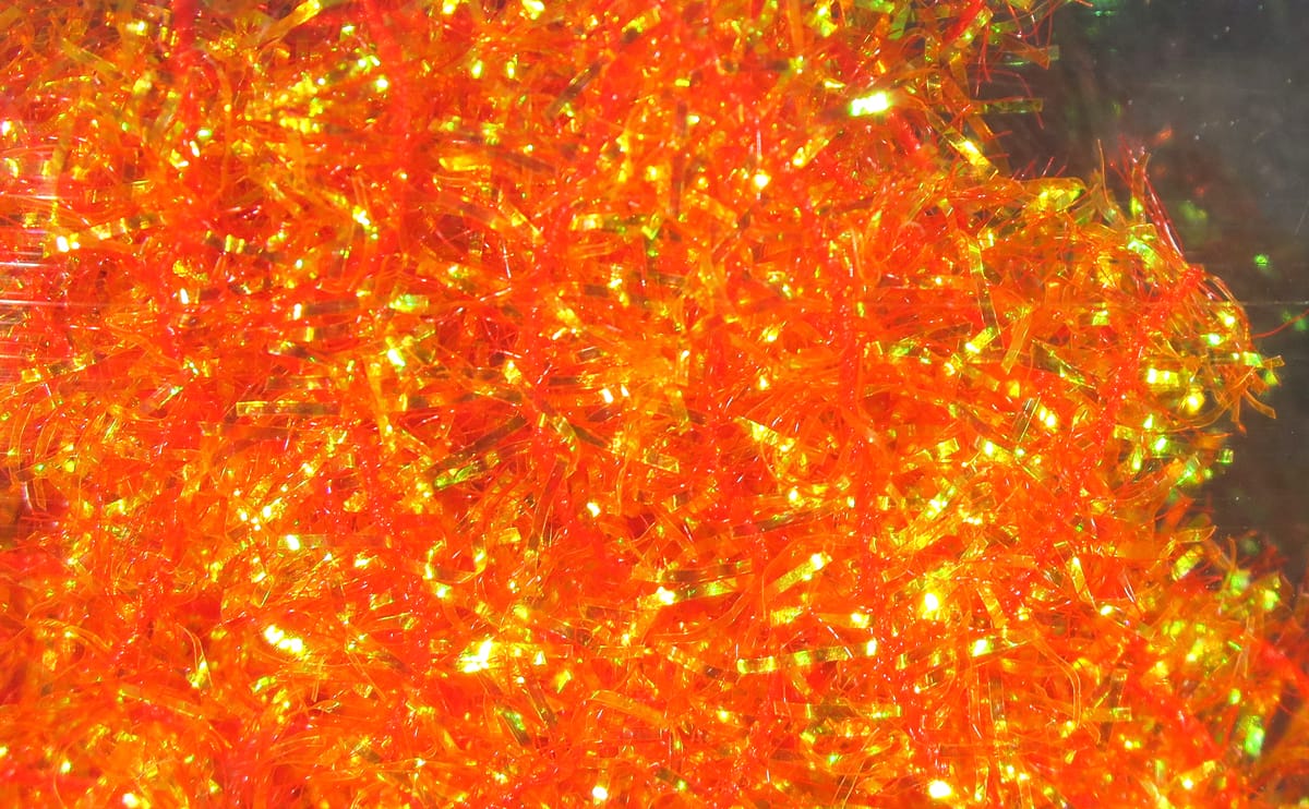 Bright orange Hareline cactus chenille with iridescent green-gold flashes, shredded synthetic fibers for fly tying