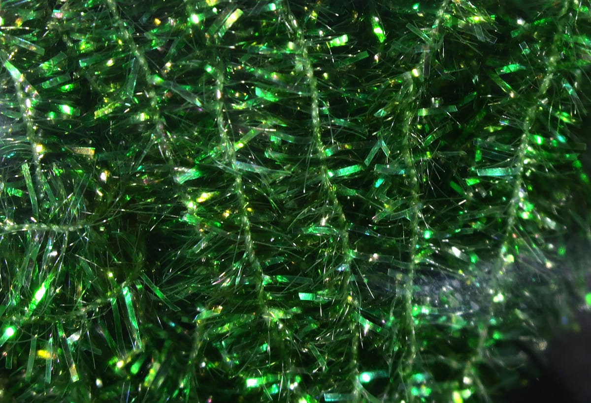 Hareline cactus chenille, close-up of bright emerald green synthetic fibers with iridescent tinsel barbs for fly tying