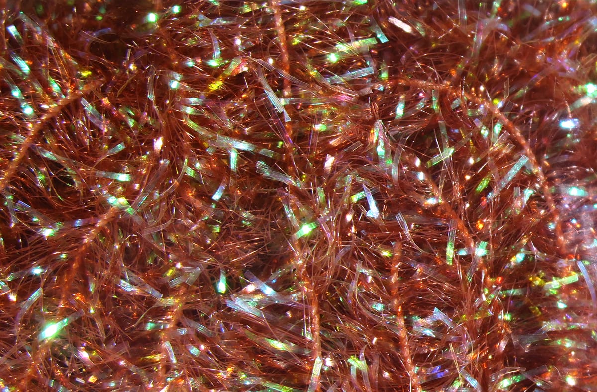 Copper-orange Hareline cactus chenille with dense fuzzy strands and iridescent flash fibers for fly tying