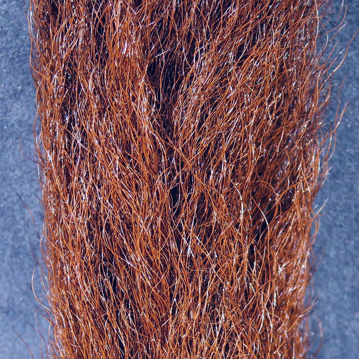 Hareline calf tails fly tying material, close-up of reddish-brown coarse calf hair fibers with natural sheen