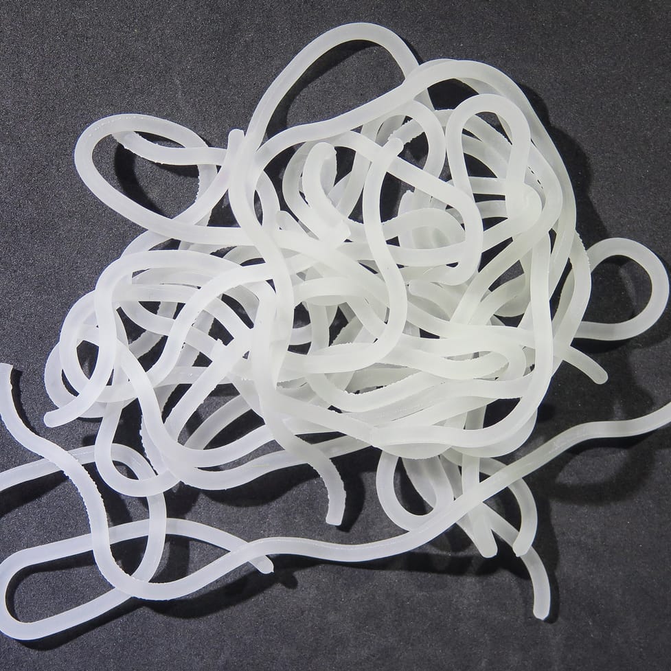 Translucent white silicone squirmy tubes for fly tying, tangled soft tubular strands with subtle ribbed texture