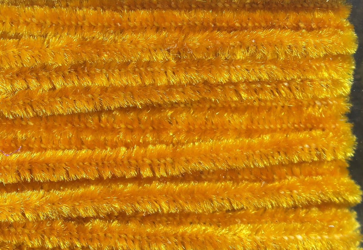 Bright golden Hareline chenille strands with shimmering fuzzy fibers, dense plush texture for fly tying