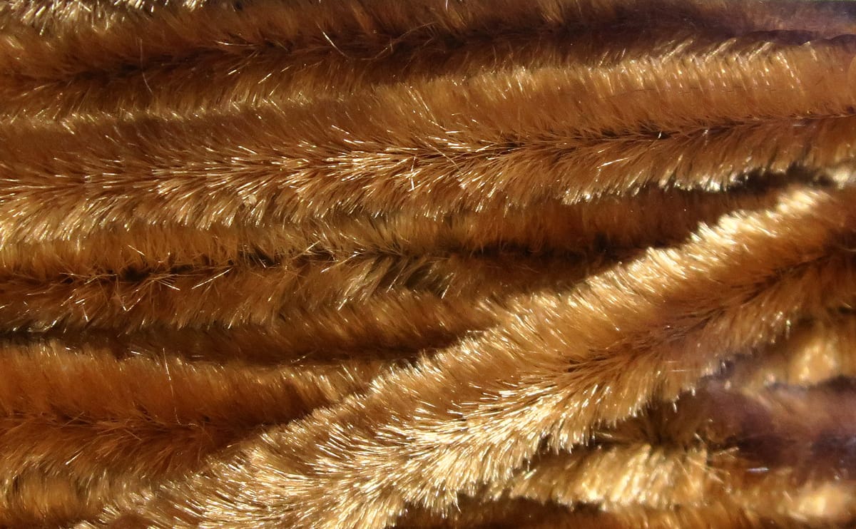 Golden brown Hareline chenille with dense, furry slightly iridescent fibers for fly tying