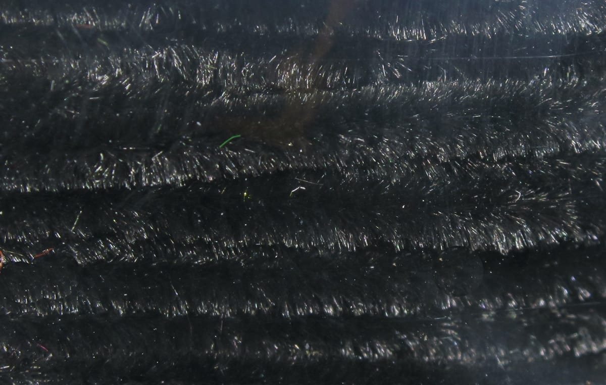 Black Hareline chenille close-up showing dense fuzzy fibers and glossy synthetic strands for fly tying.