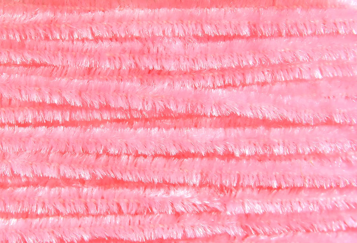Soft pale pink Hareline chenille strands with dense, shimmery synthetic fibers, fuzzy spool for fly tying