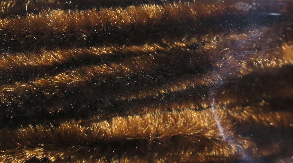 Hareline chenille fly tying material showing dark brown plush fibers with golden shimmer and dense fuzzy texture
