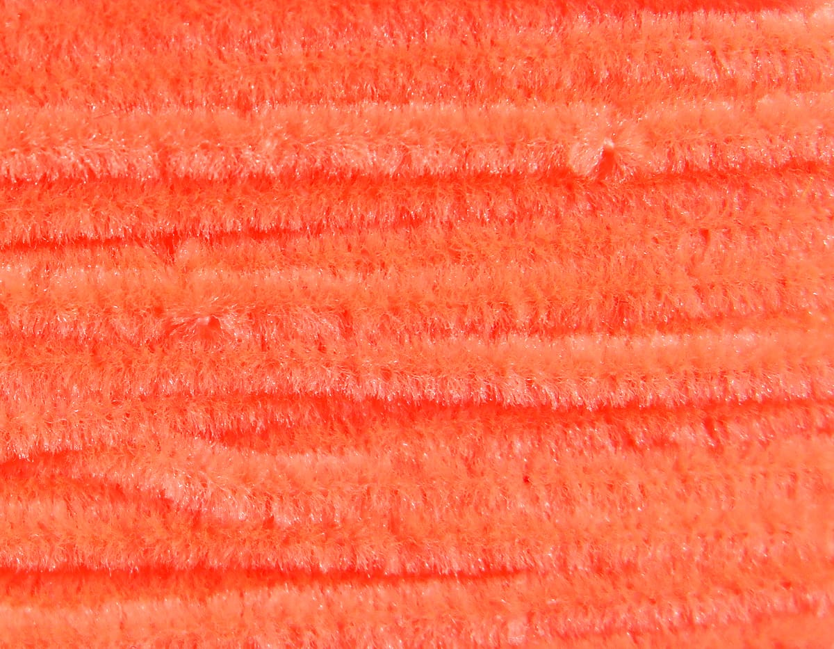 Bright orange Hareline chenille strands with fluffy, sparkly synthetic fibers for fly tying