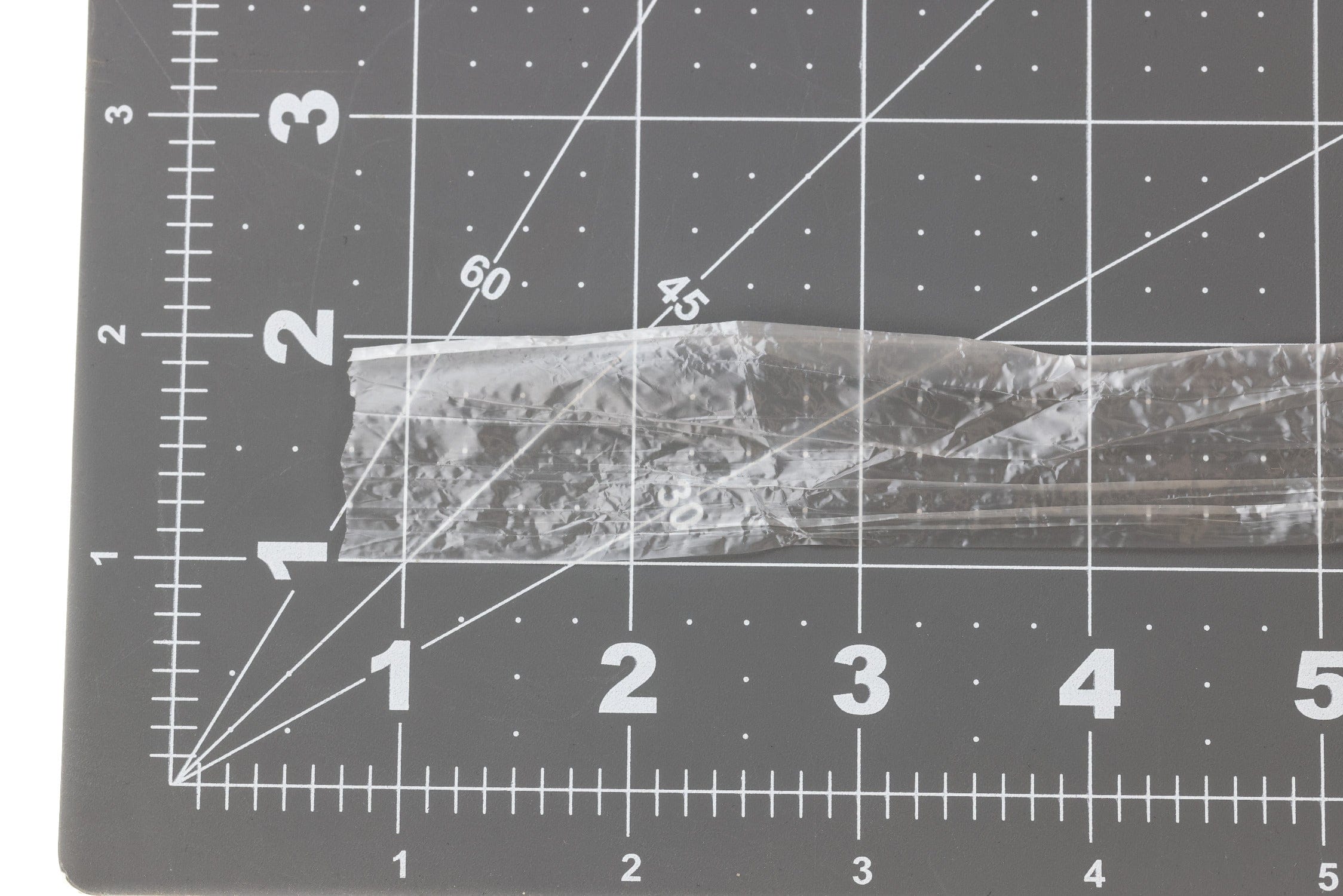 Hareline Clear Wing translucent crinkled plastic wing strip for fly tying laid on black cutting mat with white grid