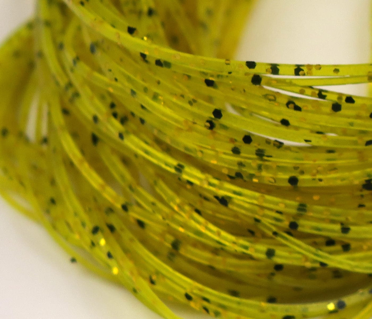 Chartreuse Hareline Crazy Legs silicone strands with black speckles and gold glitter for fly tying.