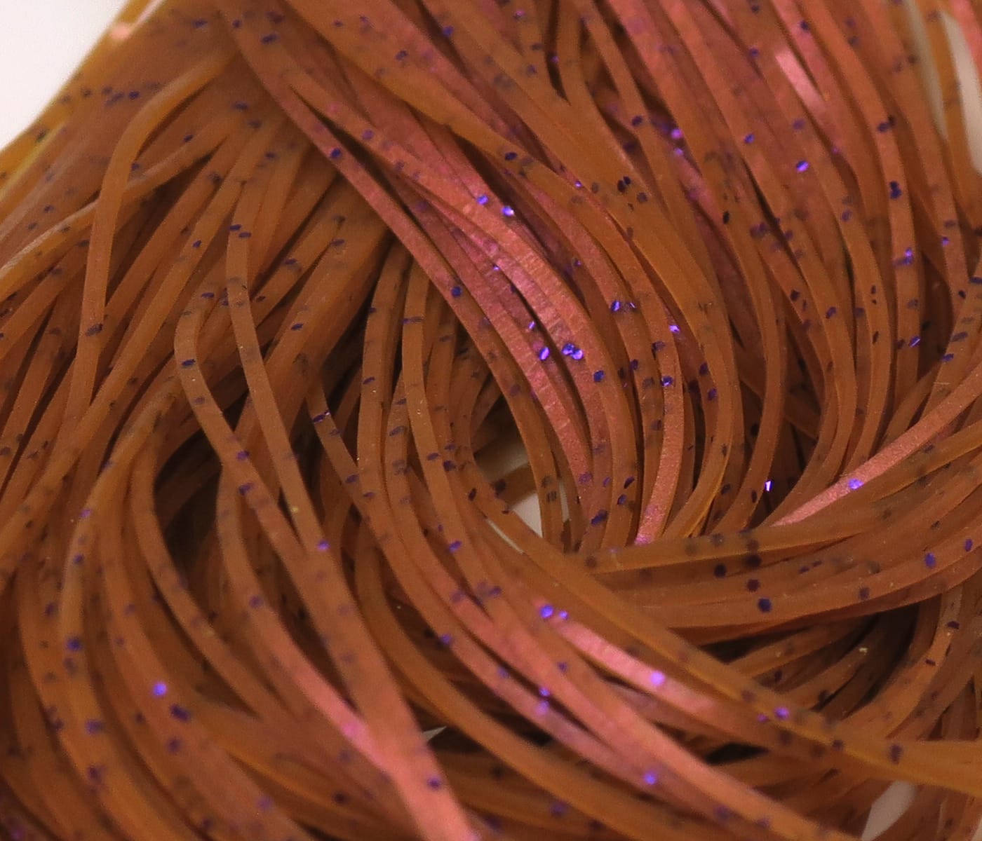 Hareline orange-brown silicone fly tying Crazy Legs strands with flat ribbon style and purple glitter flecks