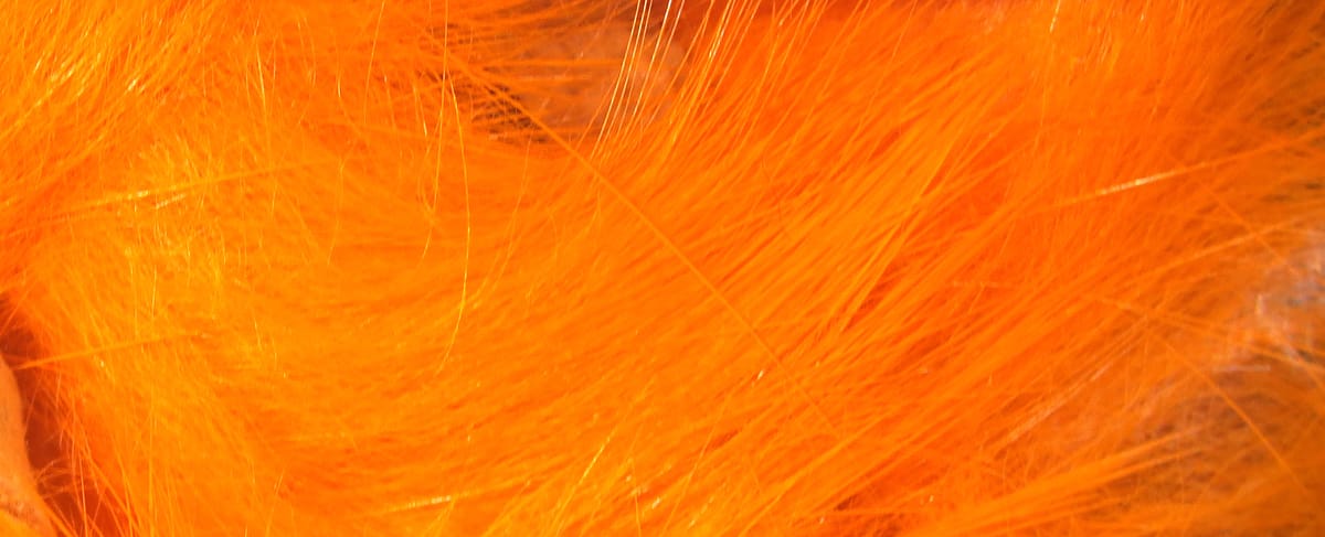 Bright orange crosscut rabbit fur strips with soft long fibers and subtle guard hairs for fly tying material