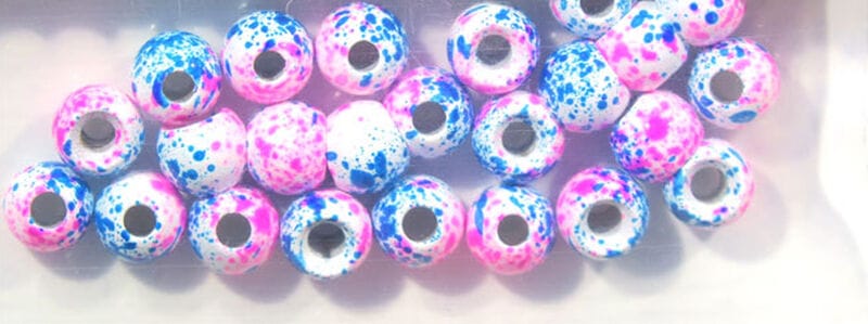 Hareline Dazzle brass beads, white round beads with pink and blue speckled splatter and visible metal cores for fly tying