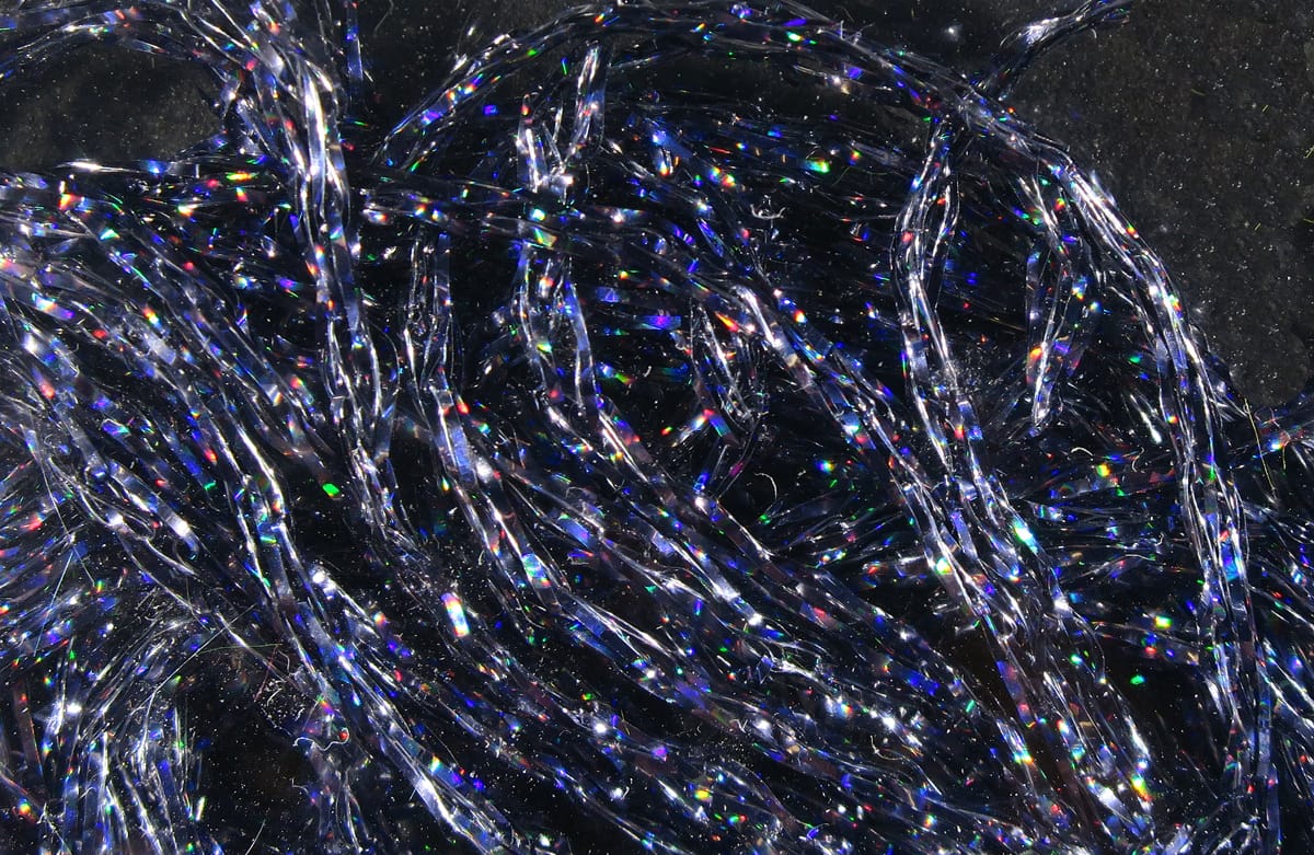Holographic silver Hareline Diamond Braid strands with twisted synthetic tinsel and rainbow flashes for fly tying