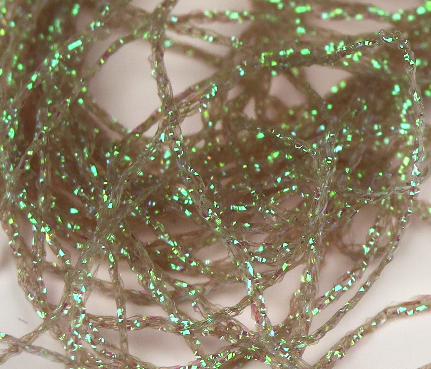Hareline Diamond Braid fly tying material: tan translucent braided strands with bright green iridescent flash