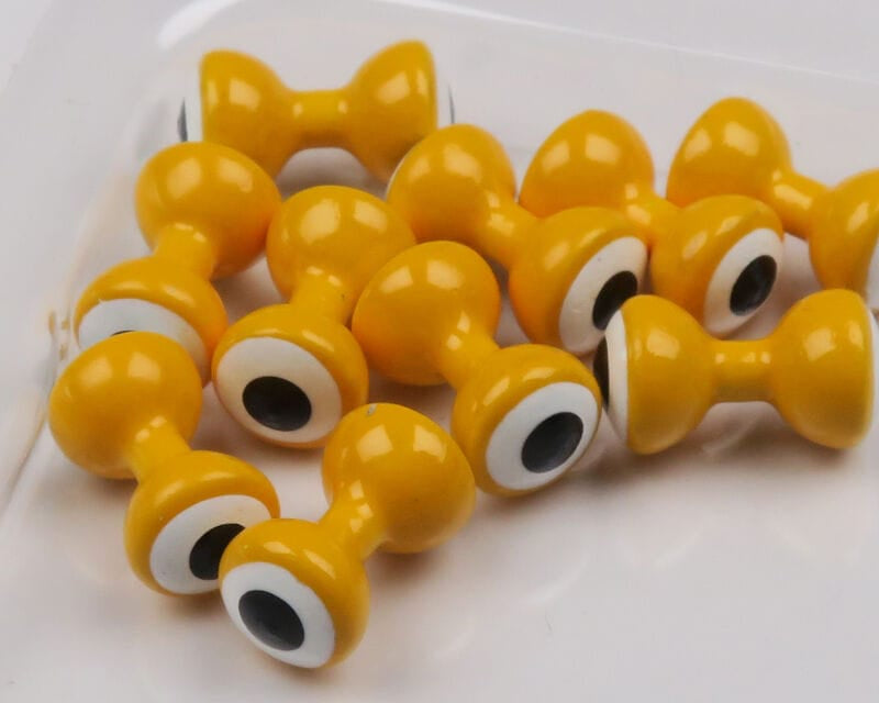 Hareline glossy mustard-yellow double-pupil brass eyes with white rings and black centers, dumbbell style for fly tying