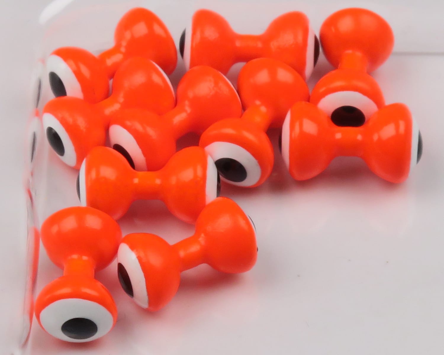 Bright orange double-pupil lead eyes for fly tying, glossy hourglass shape with white ring and black pupil