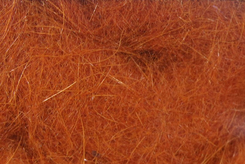 Rust-orange Hareline Dubbin fibers with fine fuzzy strands and gold guard hairs, soft dubbing for fly tying