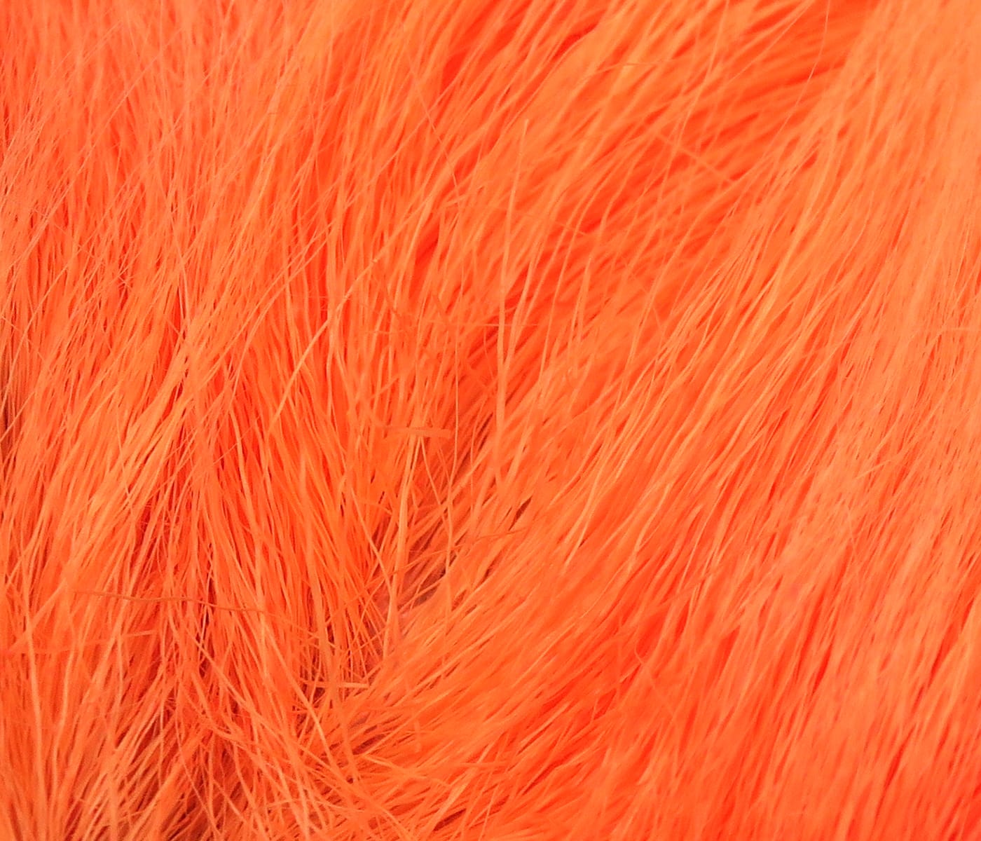 Close-up bright orange dyed deer belly hair showing fine silky fibers for fly tying