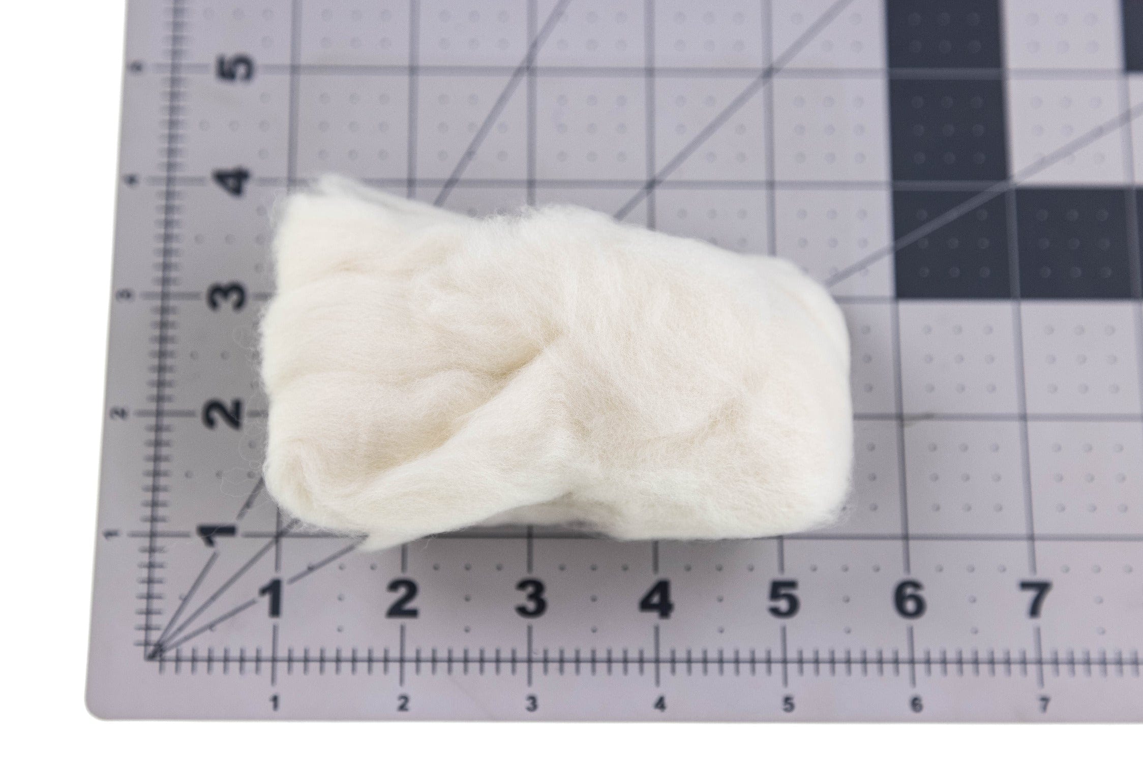 Milky white Hareline Egg Veil soft fiber bundle for fly tying on gray ruler grid mat