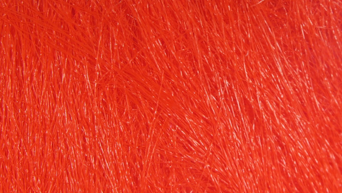 Bright fluorescent orange-red synthetic craft fur with dense, fine glossy fibers for fly tying