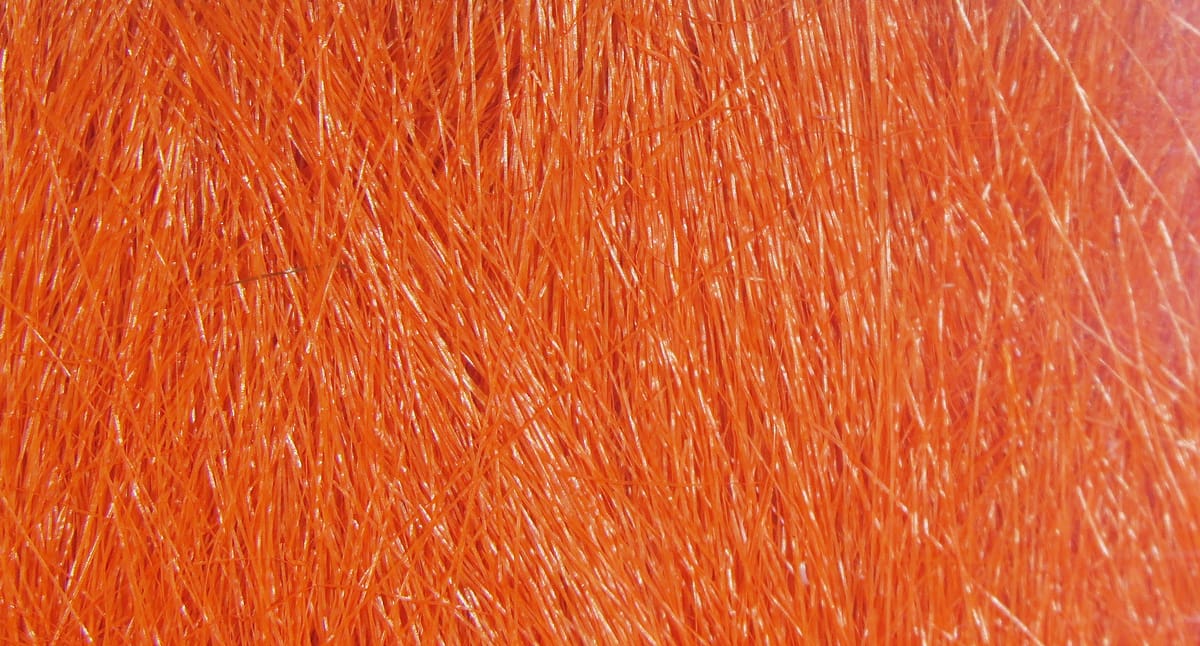 Bright orange Hareline Extra Select craft fur close-up showing fine glossy synthetic fibers for fly tying