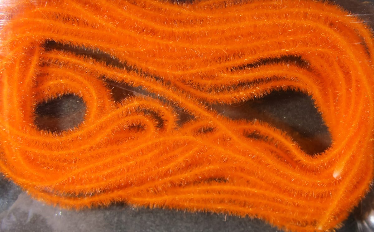 Bright orange Hareline EZ Magic Dub fly tying dubbing, fuzzy synthetic strands with subtle sparkle in coiled bundle