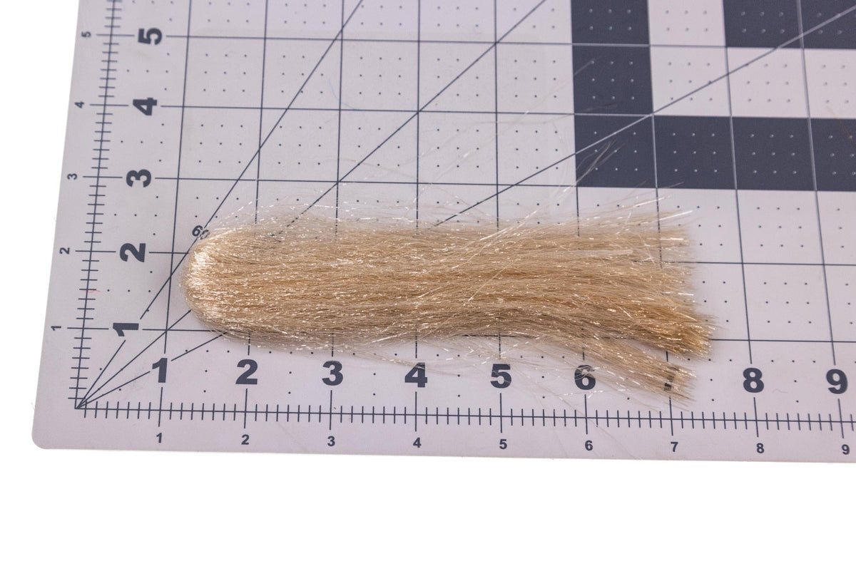 Tan Hareline finesse synthetic fibers bundle with silver flash, long loose strands for fly tying on gridded cutting mat