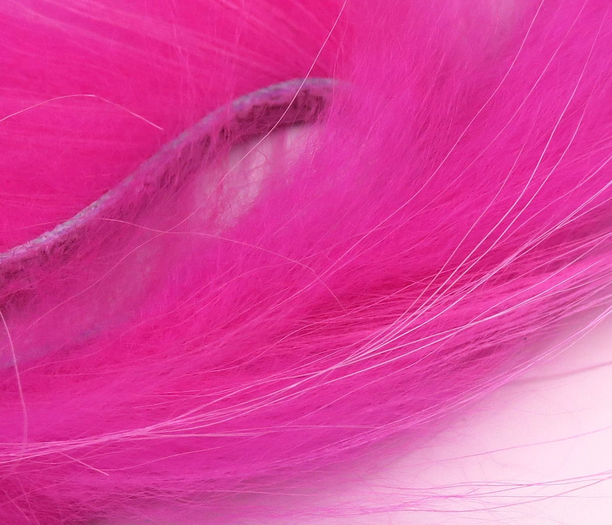 Bright hot pink raccoon zonker strip with long soft fur and visible leather belly, ideal for fly tying.