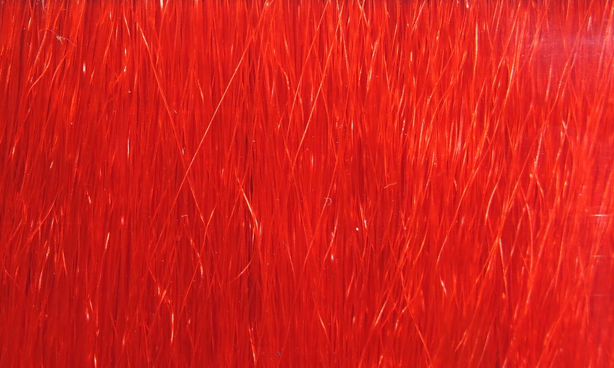 Bright red Hareline Fishair synthetic fly-tying fibers, glossy fine strands with subtle reflective sheen