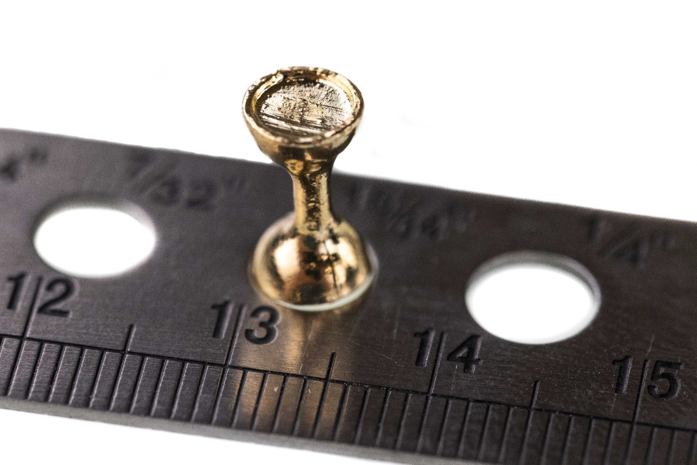 Close-up gold flat-end hourglass tungsten eye on ruler for fly tying