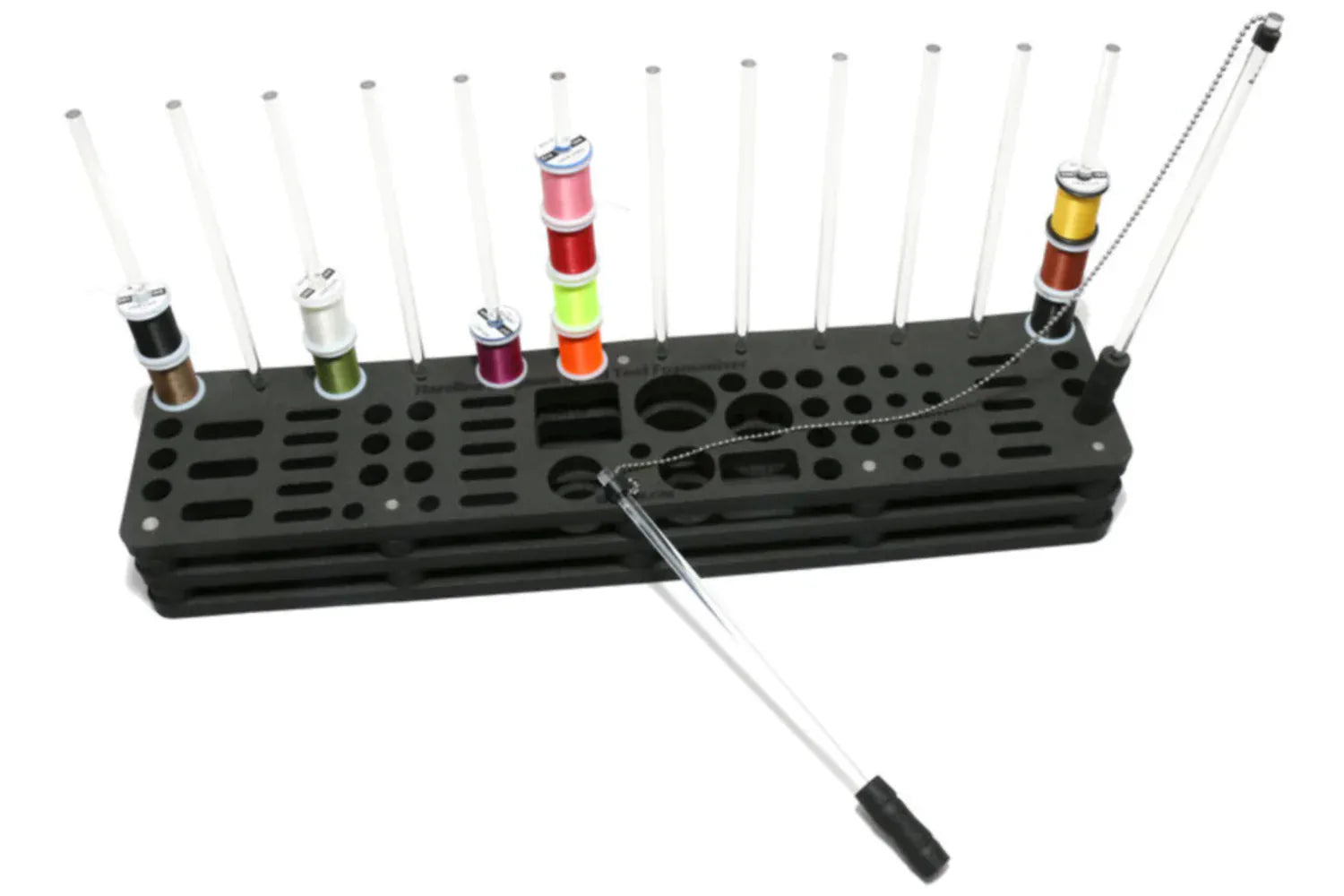 Black foam fly-tying hammock rack with clear vertical rods holding colorful thread spools, metal tool with chain attached.