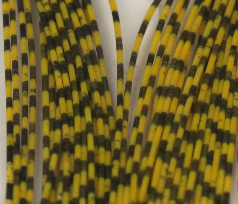 Yellow and black grizzly-barred rubber legs for fly tying, flexible striped strands bundled on white backing