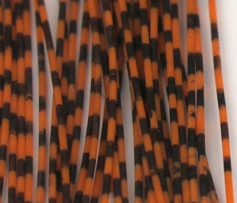 Orange and black grizzly-barred rubber legs, thin flexible rubber strands for fly tying