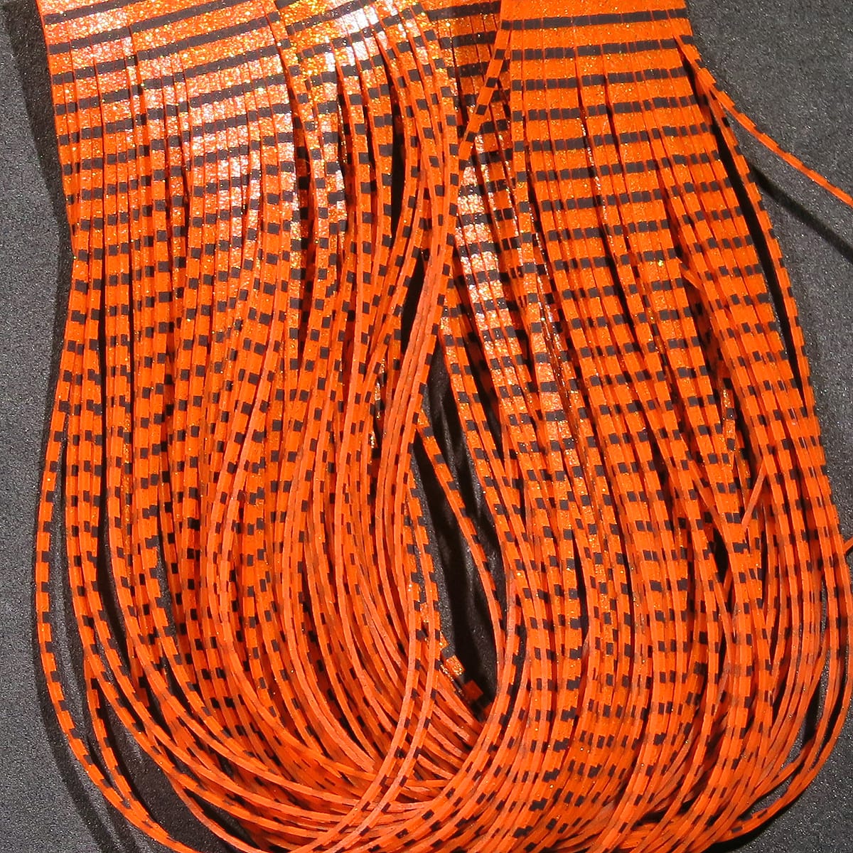 Orange and black grizzly patterned flutter legs for fly tying, thin glittery rubber strips bundled