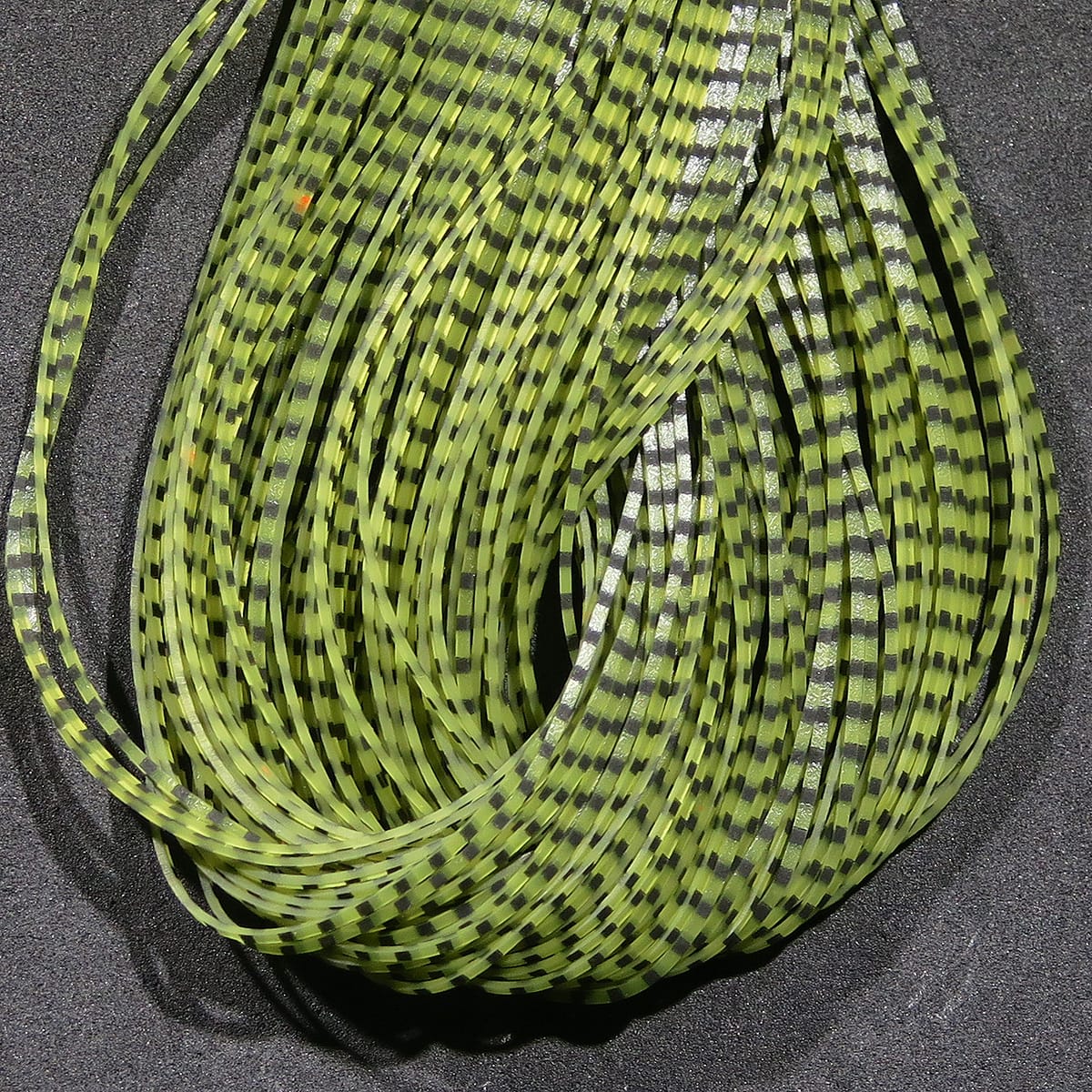 Chartreuse and black grizzly-striped synthetic flutter legs, thin flexible strips for fly tying