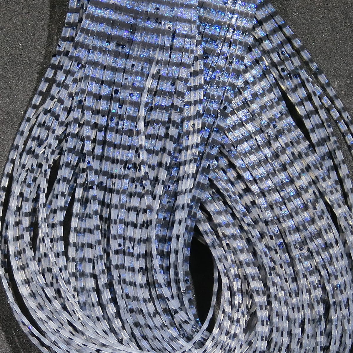 Hareline Grizzly flutter legs, translucent gray silicone strands with black grizzly bars and blue iridescent flakes, fly