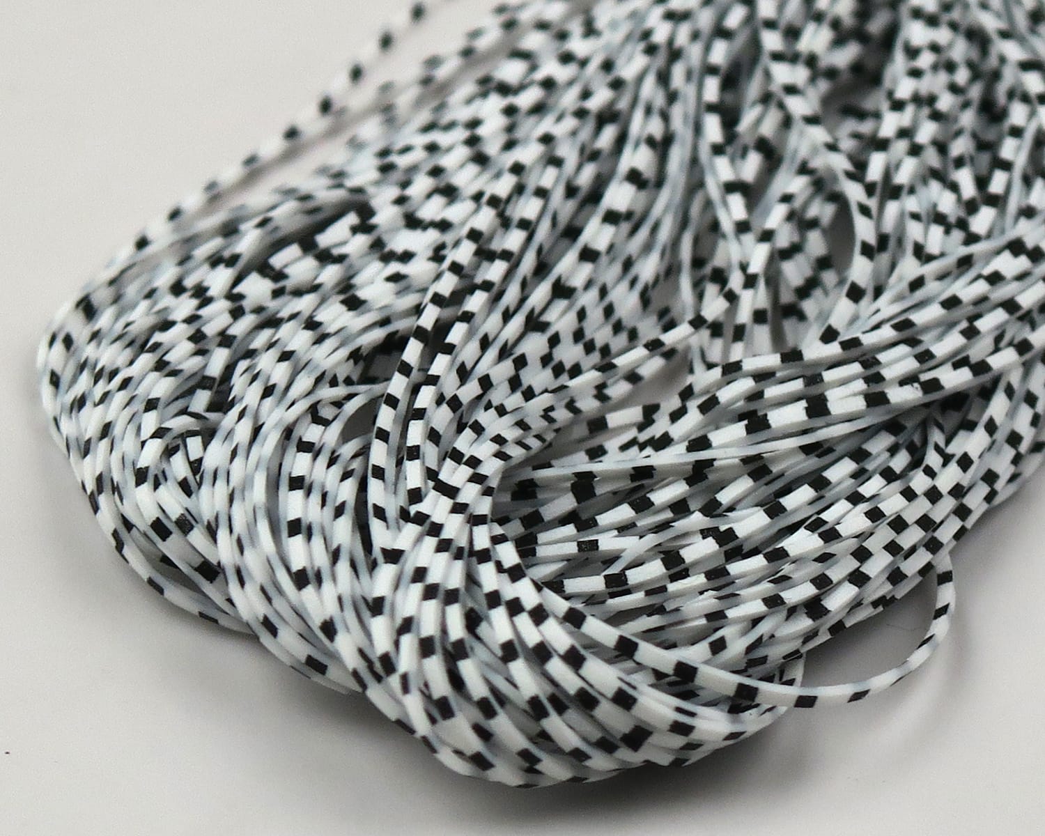 Hareline Grizzly micro legs, thin white rubber strands with black barred pattern for fly tying