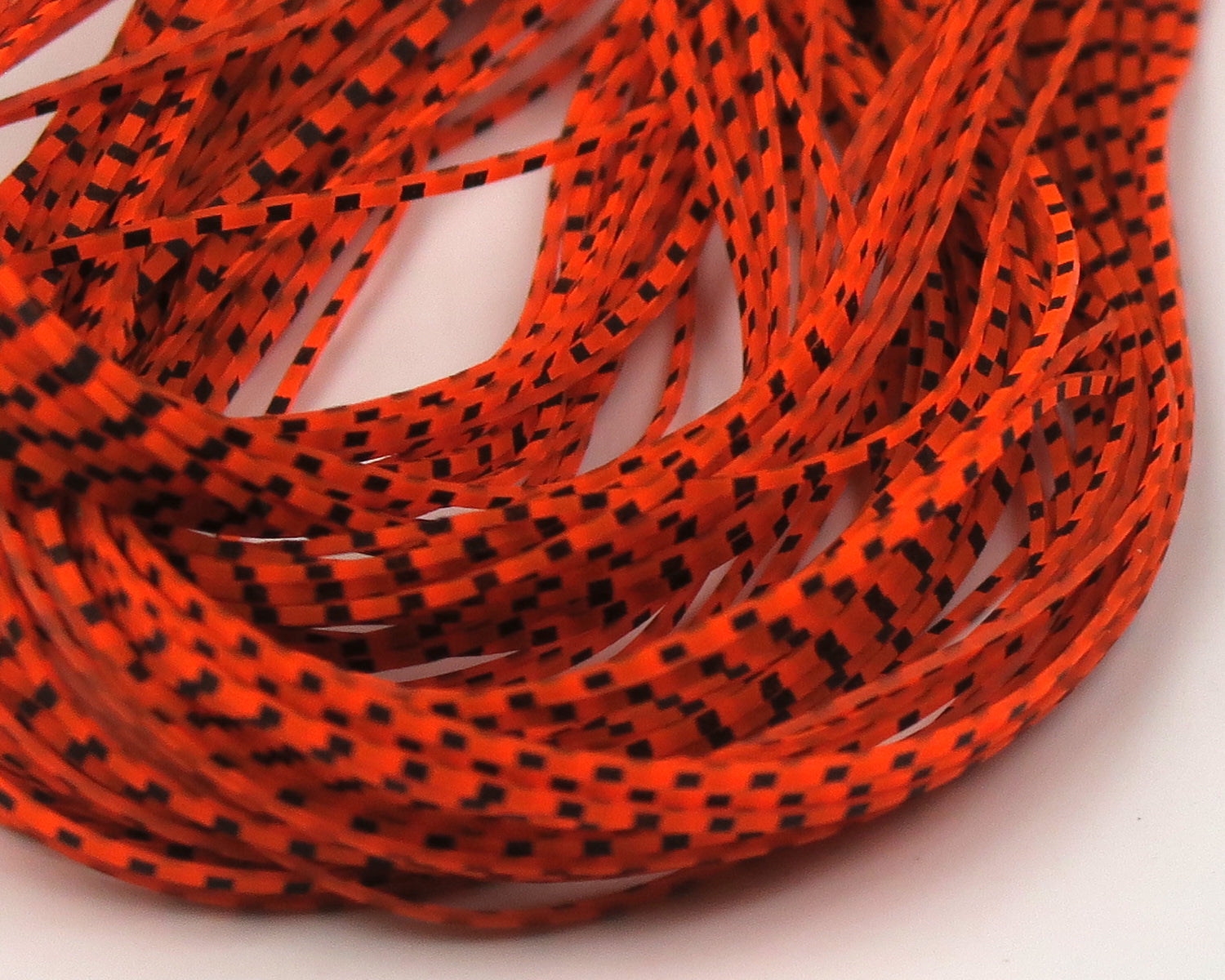 Bright orange synthetic micro legs with black grizzly checkered pattern, thin flexible fly tying strips