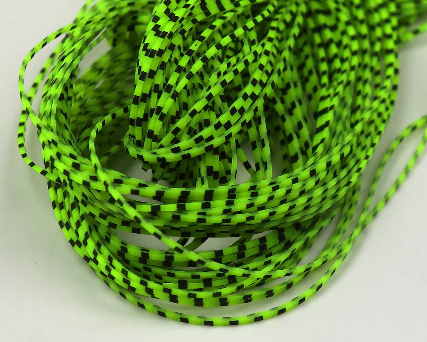 Neon chartreuse Hareline Grizzly Micro Legs: thin synthetic strands with black grizzly checkered pattern for fly tying