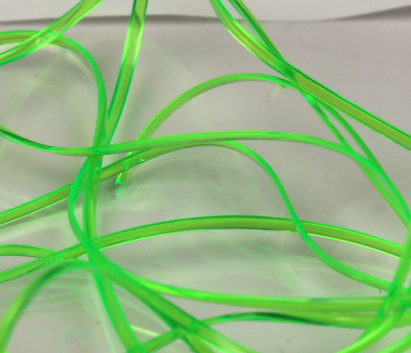 Neon chartreuse translucent half-round D-rib strands for fly tying, flexible plastic ribbing with glossy finish