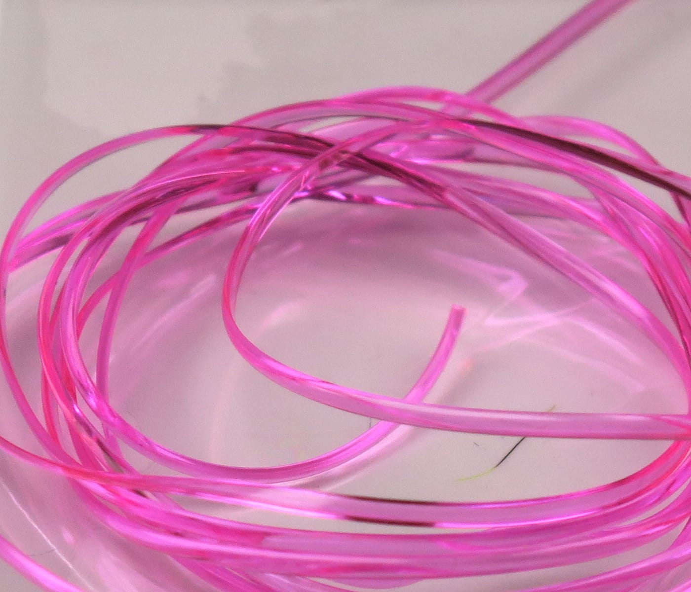 Shiny hot pink Hareline half-round D-rib coils, translucent synthetic rib for fly tying
