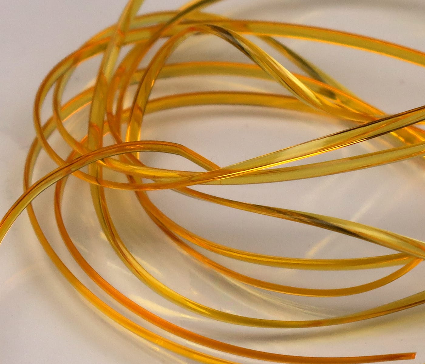 Coiled translucent amber half-round D-rib plastic strips for fly tying with glossy thin ribbing