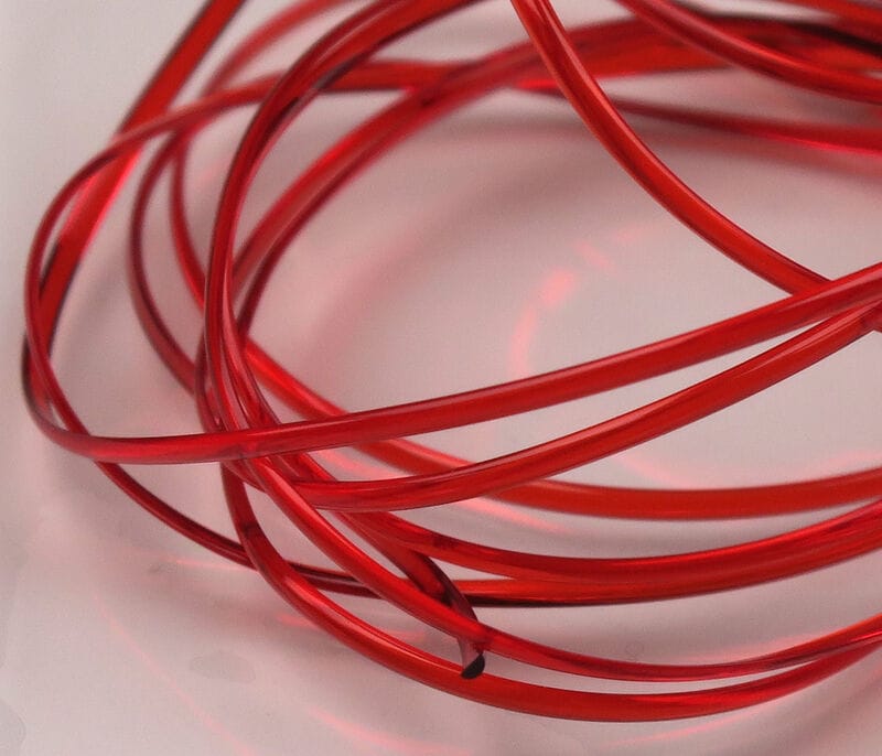 Red translucent Hareline half-round D-rib coils, glossy plastic fly-tying rib material in coiled strands
