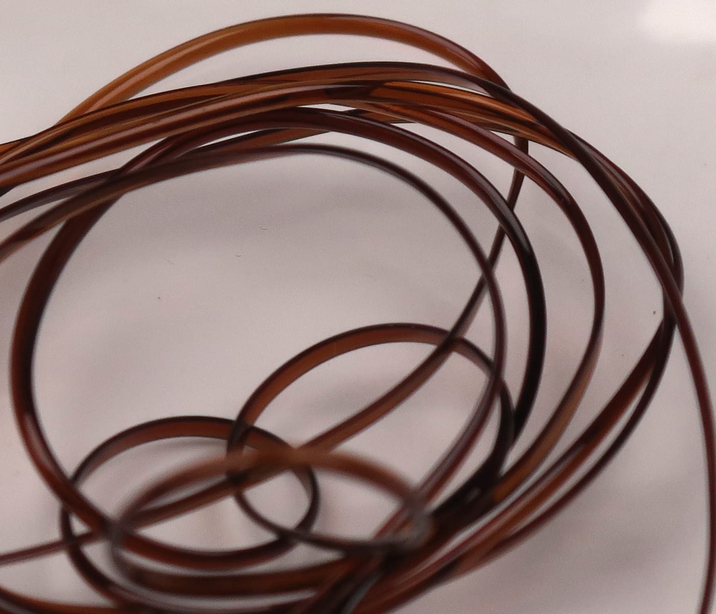 Hareline half-round D-Rib coil, translucent amber-brown glossy plastic rib used for fly tying