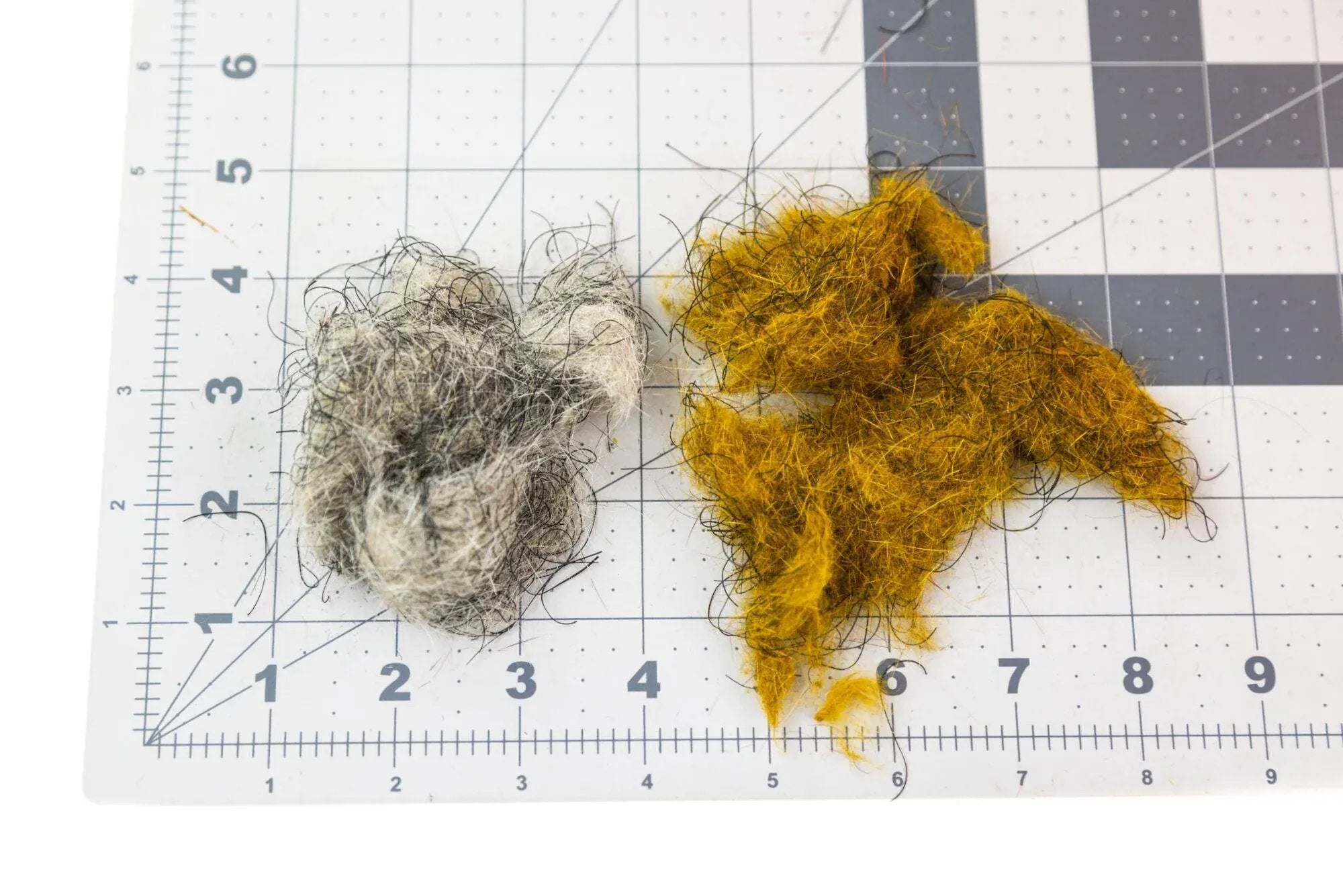 Hare'E Wiggle Dub fly tying dubbing clumps in gray and golden-olive with dark guard hairs on grid