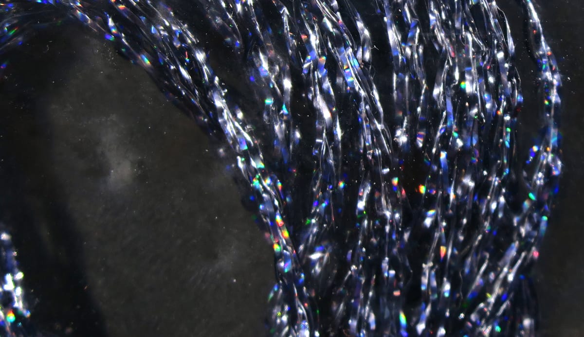 Hareline holographic braid: twisted navy-blue iridescent synthetic strands with rainbow flashes for fly tying