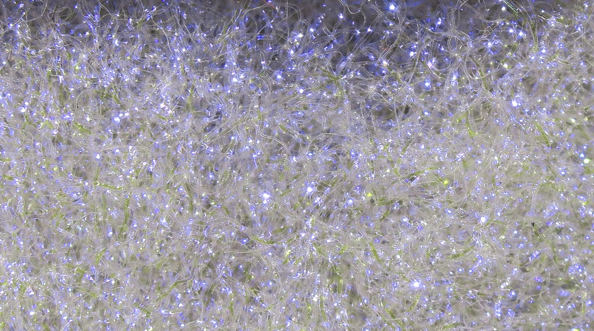Hareline Ice Dubbing translucent white synthetic fibers with iridescent sparkle and subtle lime-green strands for fly tying