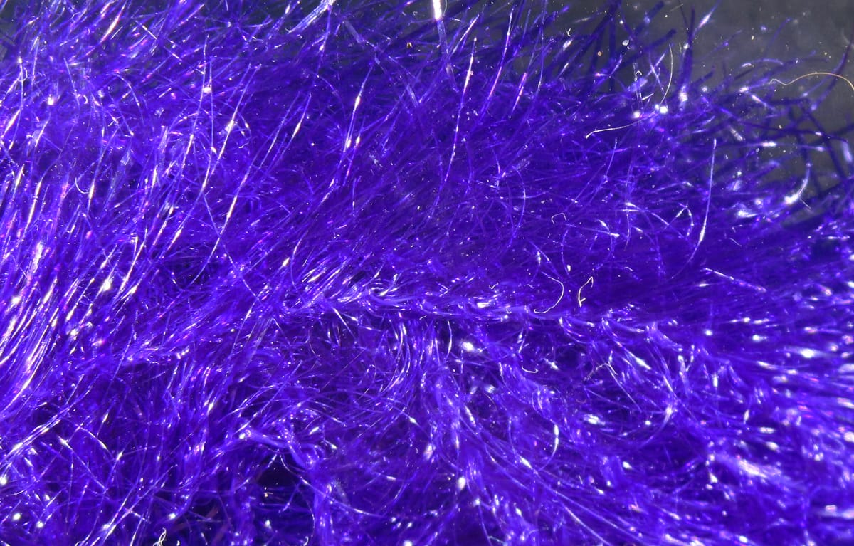 Vibrant purple Krystal Hackle closeup showing iridescent synthetic hackle fibers with shimmering tinsel strands for fly tying