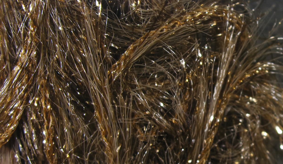 Hareline Krystal Hackle brown synthetic fibers with gold tinsel strands, glittery iridescent fly tying material